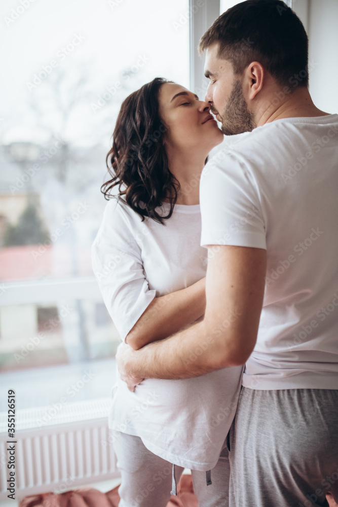 Naklejka premium Stunning sensual intdoor portrait of young stylish fashion couple in love. Woman and man embrace and want to kiss each other. They are smiling and looking to each other