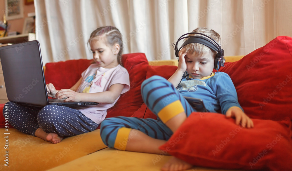 Gadget dependence, digital native generation alpha, kid lying on sofa and using gadgets at home Gadget dependence, digital native generation alpha, kid lying on sofa and using gadgets at home
