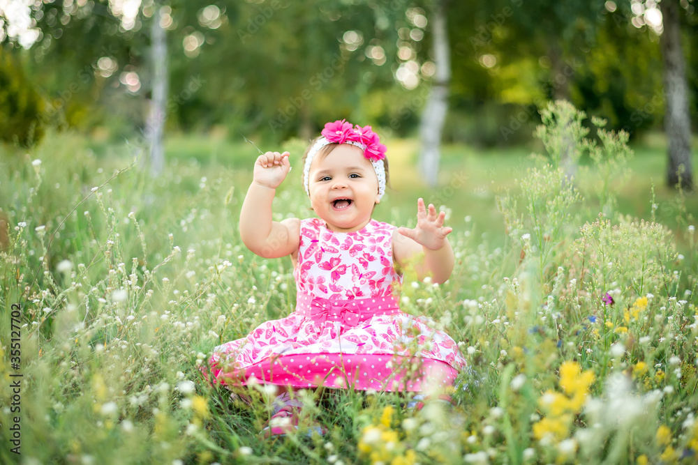 Children's day, a girl in the Park in the summer sitting on the grass Children's day, a girl in the Park in the summer sitting on the grass