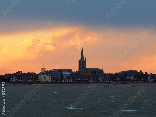Orange sunset with clouds parting after a stormy day over St Nicholas Church on the seafront, Harwich, Suffolk, UK