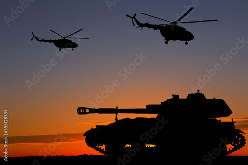Fotografie Silhouettes of army tank and helicopters at sunset outdoors