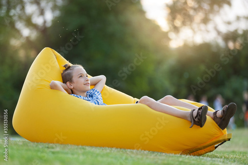 boy resting in nature, lies on a yellow air sofa, concept photo