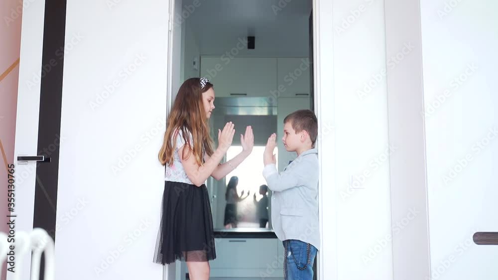 two stylish cheerful children brother and sister, a little girl and a boy clapping their hands, playing in their room, fooling around and laughing. Laughter and joy at home two stylish cheerful children brother and sister, a little girl and a boy clapping their hands, playing in their room, fooling around and laughing. Laughter and joy at home