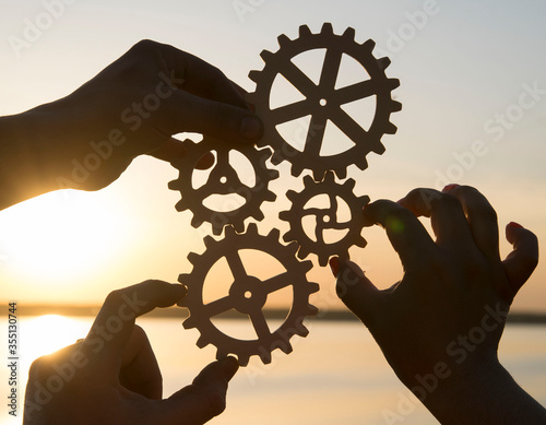 Gears in the hands of people against the sky