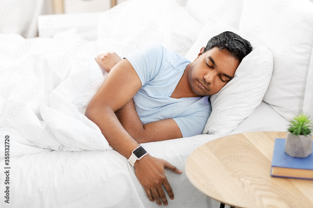 people, bedtime and rest concept - indian man with smart watch sleeping in bed at home people, bedtime and rest concept - indian man with smart watch sleeping in bed at home