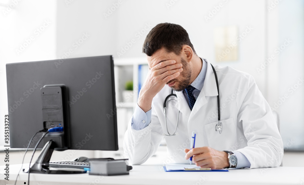 healthcare, medicine and people concept - stressed male doctor with clipboard at hospital