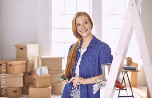 Beautiful young woman on a white wooden stepladder. Ready to repair the room. Women housework concept