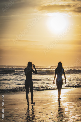 Two girls walking on the beach of Semyniak in Bali at sunset