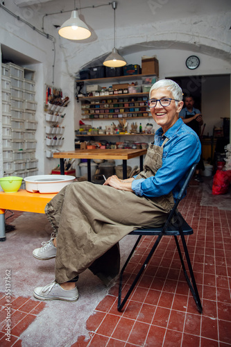 Senior woman sitting on chair, smoking and relaxing in pottery workshop