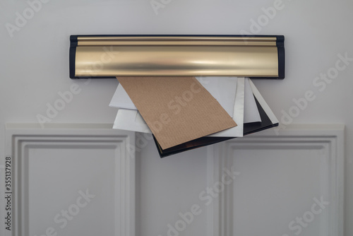 Letters, flyers and utility demands posted through a domestic letterbox.