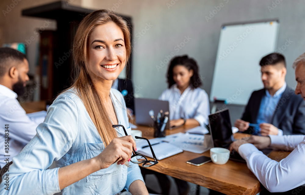 Businesswoman Smiling Sitting On Meeting With Coworkers In Office Businesswoman Smiling Sitting On Meeting With Coworkers In Office