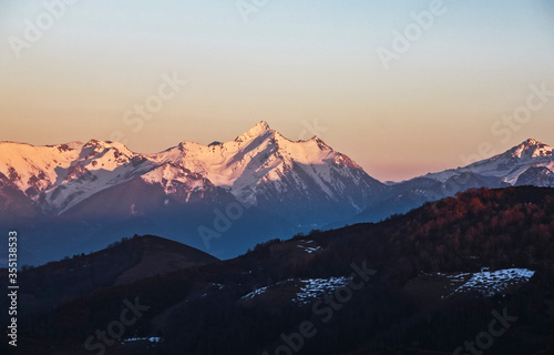 Landscape of high mountains covered by snow in a sunset with the sun hitting the peaks and the shade in the valleys