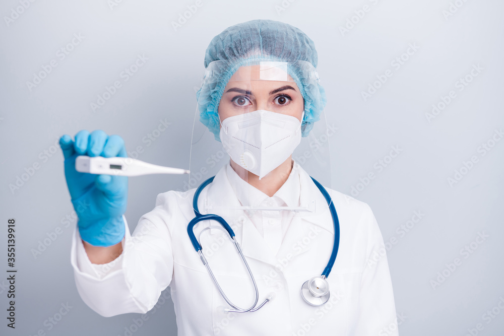 Photo of infection disease virologist doctor lady hold thermometer big eyes high temperature wear coat respirator mask facial plastic protection surgical hat gloves isolated grey background Photo of infection disease virologist doctor lady hold thermometer big eyes high temperature wear coat respirator mask facial plastic protection surgical hat gloves isolated grey background