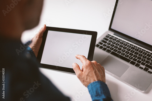 Male hand pointing at tablet screen. Businessman working remotely from home or coworking place.