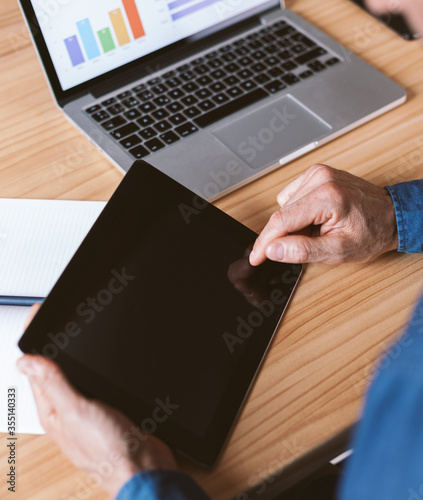 Male hand pointing at tablet screen. Businessman working remotely from home or coworking place.
