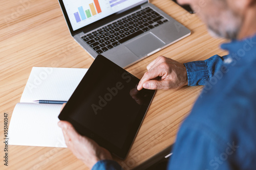 Male hand pointing at tablet screen. Businessman working remotely from home or coworking place.