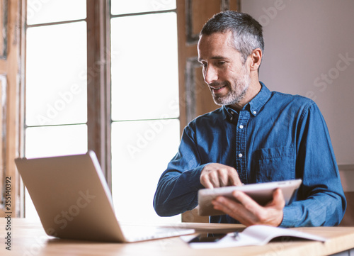 Good looking middle aged modern man is having a video meeting with colleagues or family or friends, from home