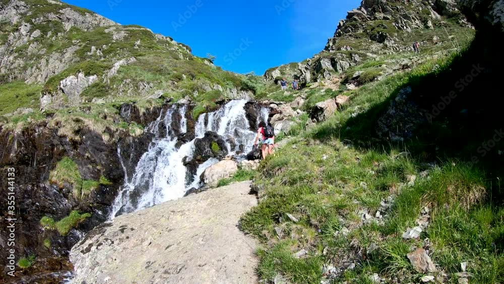 Female hiker near wild splashing waterfall. Ayous lake french Pyrenees Female hiker near wild splashing waterfall. Ayous lake french Pyrenees