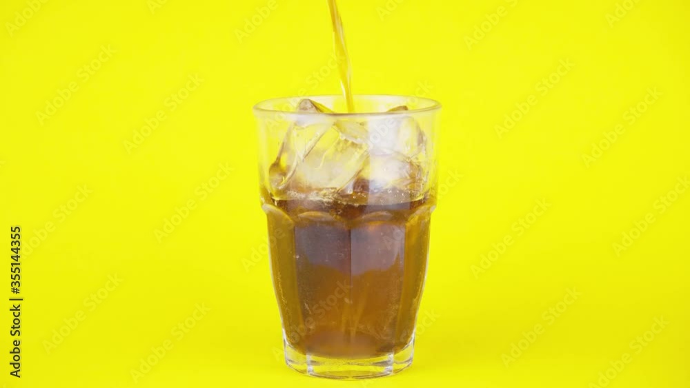 close up serving a liquid glass of cola on a yellow background. Isolated sparking soda. Concept of fluid beverage. close up serving a liquid glass of cola on a yellow background. Isolated sparking soda. Concept of fluid beverage.