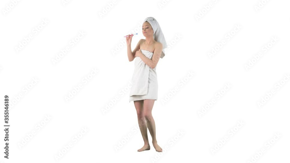 Young woman in bath towel singing and dancing carefree listening music holding toothbrush isolated on solid white background. Young woman in bath towel singing and dancing carefree listening music holding toothbrush isolated on solid white background.