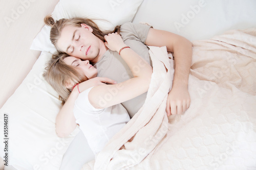a young long-haired couple man and woman sleep in a hug in bed. The concept of healthy sleep in a young family