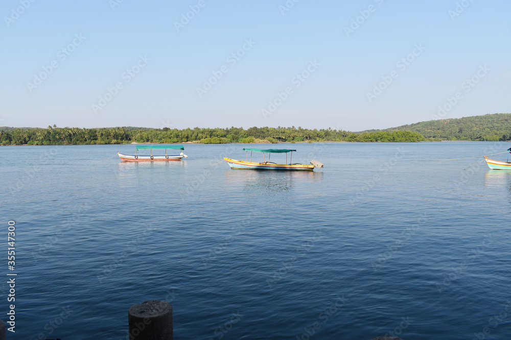 Boats in blue water with trees in background