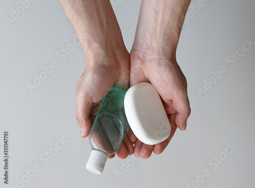 Man holding antibacterial gel hand sanitizer and antibacterial soap in his hands, coronavirus protection concept, medical background, clean hands backdrop