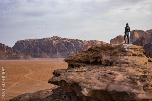 Man on top of the mountain in Wadi Rum desert in Jordan looking panorama