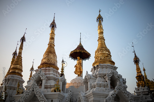 White and golden stupas with golden figure at the center. Sunset time. Inside the Shwedagon pagoda. Yangon - Rangoon  Myanmar - Burma  Southeast Asia