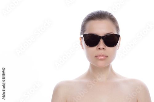 Beautiful young woman in sunglasses. With clean, fresh skin on the face and gloss on beautiful lips. Horizontal. place for text. on white background