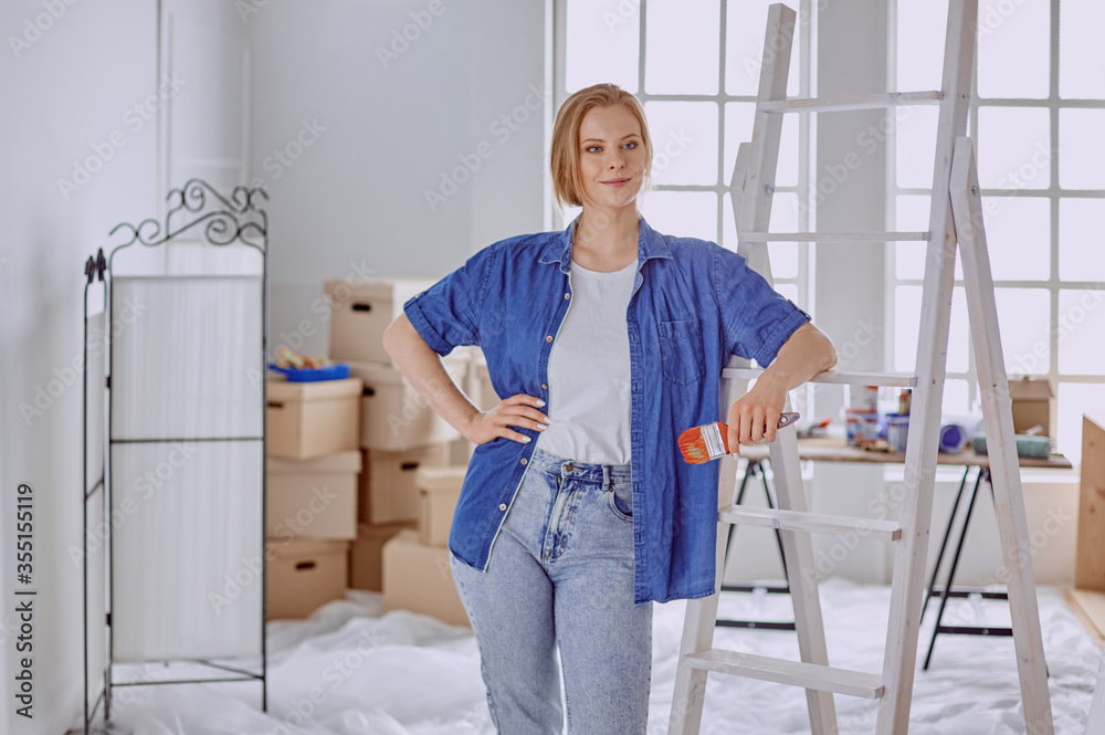 Beautiful young woman on a white wooden stepladder. Ready to repair the room. Women housework concept