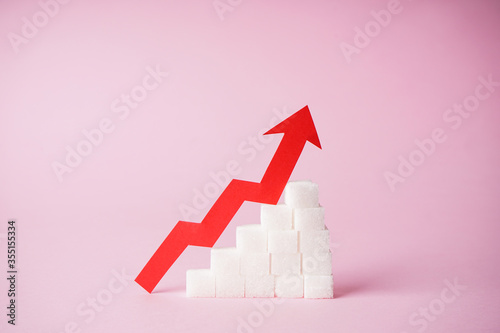 Increase in blood sugar levels, the graph of growth of the sugar cubes and arrow on top on a pink background, close-up. Diabetes concept. photo