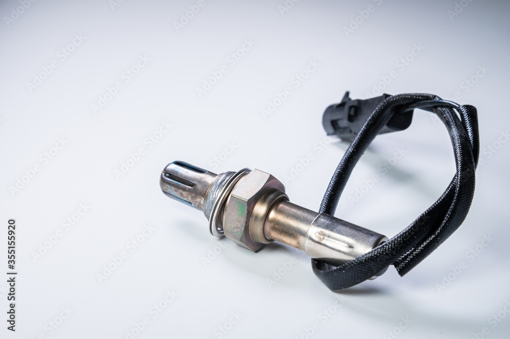 The oxygen sensor is a new lambda sensor. Spare parts on the car on a gray gradient background The oxygen sensor is a new lambda sensor. Spare parts on the car on a gray gradient background