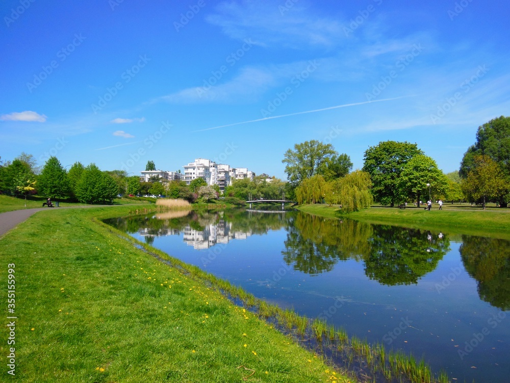 Beautiful spring landscape with pond and bright, colorful trees in the park. Kepa Potocka, Warsaw, Poland. The oxbow lake of the Vistula at Kepa Potocka - 18 hectares green rectreation area Beautiful spring landscape with pond and bright, colorful trees in the park. Kepa Potocka, Warsaw, Poland. The oxbow lake of the Vistula at Kepa Potocka - 18 hectares green rectreation area