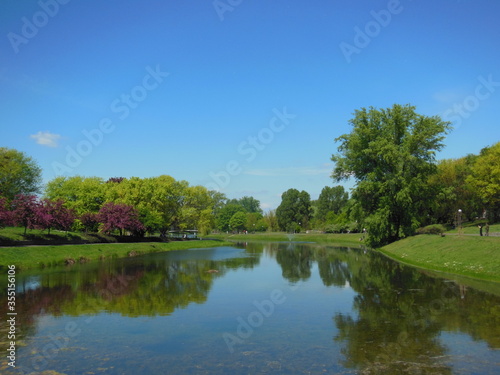 Fototapeta Naklejka Na Ścianę i Meble -  Beautiful spring landscape with pond and bright, colorful trees in the park. Kepa Potocka, Warsaw, Poland. The oxbow lake of the Vistula at Kepa Potocka - 18 hectares green rectreation area 