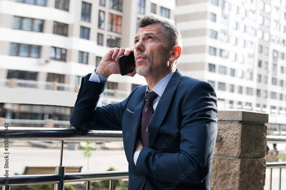 Businessman talking on cell phone against the building with a glass facade Businessman talking on cell phone against the building with a glass facade