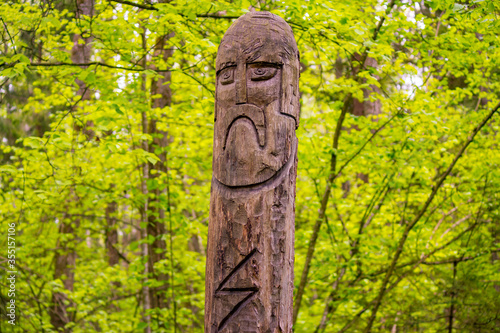 The image of the Slavic deity Veles carved from a tree trunk on a neo-Pagan temple in the forest. Kaluzhskiy region, Russia. Veles - the god of cattle breeding, wealth and wisdom © PhotoChur
