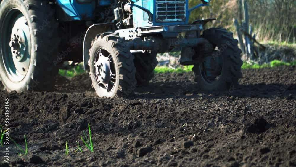 The tractor cultivates and cuts furrows in the field. Tractor work in the black soil field in the village The tractor cultivates and cuts furrows in the field. Tractor work in the black soil field in the village