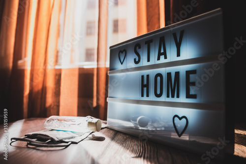 oronavirus home sign lightbox with text STAY HOME glowing in light. COVID-19 banner to promote self isolation staying at home. Apartment background photo