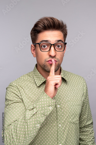Tableau sur toile Young man telling secret and keeping forefinger on lips