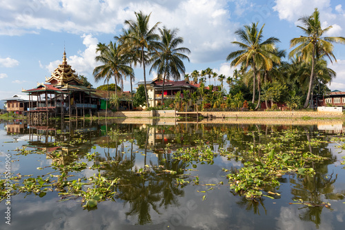 Buddhist monastery Nga Phe Kyaung surrounded by vegetation  reflected on the waters of Inle lake  Myanmar  Burma  southeast Asia. Symmetrical picture. Tropical vegetation. Palm trees