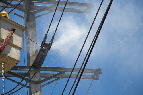 Foto Electricity authority clean the ceramic insulator on the electric pole by high pressure washers