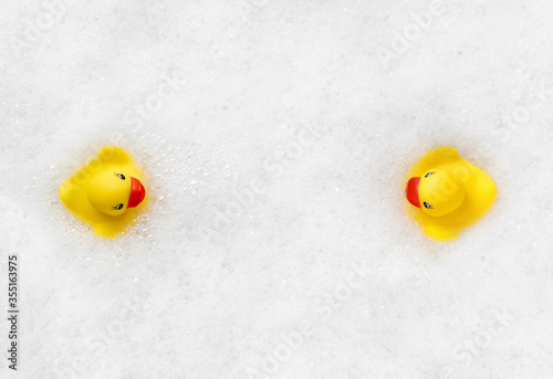 High Angle View of yellow rubber duck in bath swimming in foam water. Yellow rubber ducklings in soapy foam.