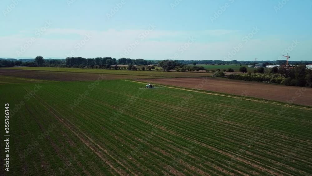 Farmer driving tractor to water his crops on a sunny day in Europe filmed by a drone Farmer driving tractor to water his crops on a sunny day in Europe filmed by a drone