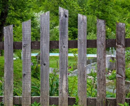 Fence from the house. Guarding the property. In the background greenery, grass and meadows © HappyLenses
