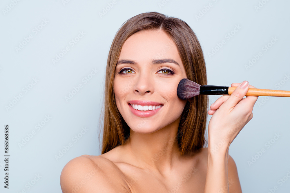 Close up photo portrait of cute pretty attractive brunette she her lady holding applicator in hand doing contouring on cheekbones isolated on grey background Close up photo portrait of cute pretty attractive brunette she her lady holding applicator in hand doing contouring on cheekbones isolated on grey background