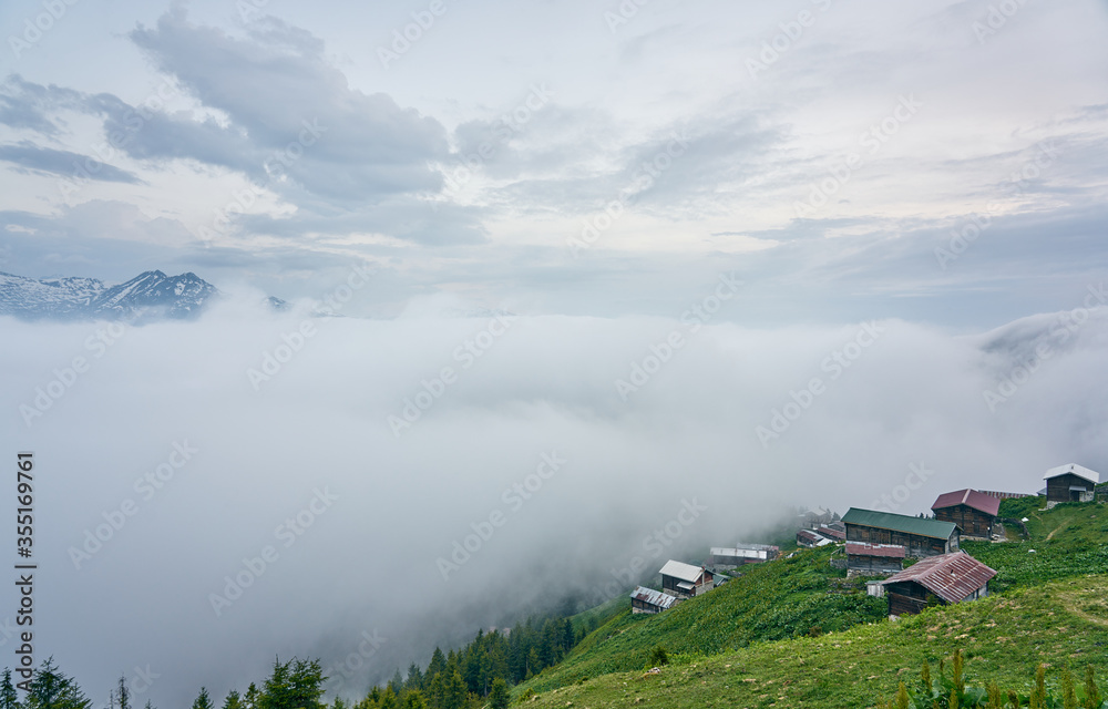 Traditional wooden houses and sea of clouds with snowy mountain. Landscape photo was taken at Pokut Plateau, Rize, northeastern Karadeniz (Black Sea) region of Turkey.