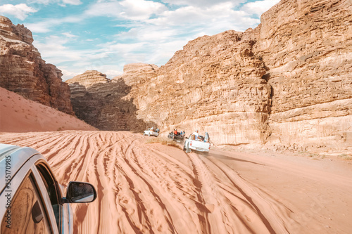 traditional tourist entertainment is a ride on jeeps on the desert Sands, powerful cars drive in hot Sunny weather through the desert through canyons and rocks, white and black cars, pink Sands