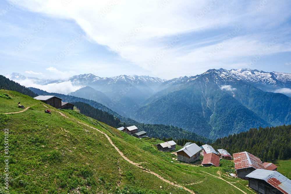 Traditional wooden houses and sea of clouds with snowy mountain. Landscape photo was taken at Pokut Plateau, Rize, northeastern Karadeniz (Black Sea) region of Turkey.