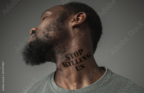 Close up black man tired of racial discrimination has tattooed slogan stop killing us on his neck. Concept of human rights, equality, justice, problem of violence and racism, discrimination.